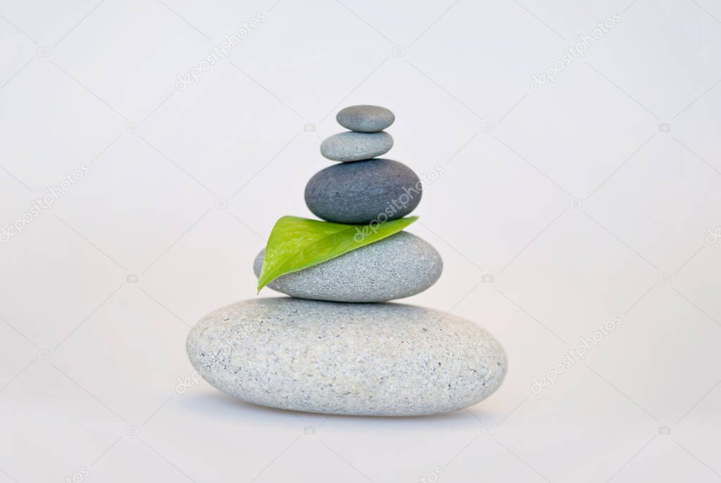 Balanced pebble stone cairn across a white background