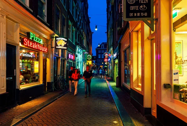 荷兰阿姆斯特丹 2015年7月7日 在荷兰首都阿姆斯特丹的老历史地段 狭窄街道上经过灯火通明的商店 餐馆和酒吧的人们 — 图库照片