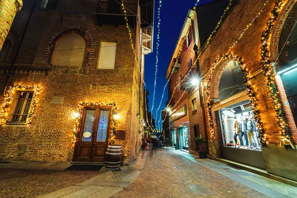 Kopfsteinpflaster Abendstraße beleuchtet mit Weihnachtsbeleuchtung in alba, italien. — Stockfoto