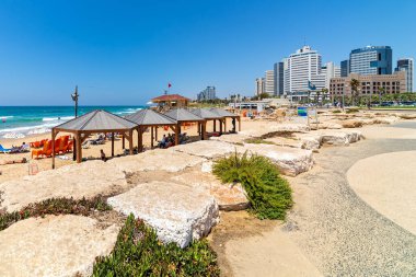 TEL AVIV, ISRAEL - 18 Temmuz 2018: İsrail 'in ekonomik ve teknolojik merkezi, Akdeniz kıyı şeridinde şehir Tel Aviv' de mavi gökyüzü altında modern iş binaları olarak kamu plajı boyunca gezinti manzarası.