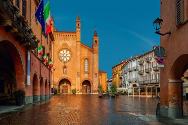 Şehir meydanı, eski evler ve San Lorenzo katedrali Alba, Piedmont, Kuzey İtalya 'da gökkuşağı altında güneşle aydınlatılmış..