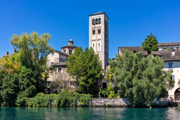 Piedmont, Kuzey İtalya 'daki San Giulio Gölü' ndeki küçük San Giulio adasındaki yeşil ağaçların arasında ortaçağ kulesi ve eski manastır..