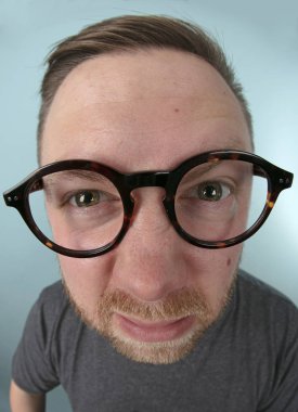 Büyük giyen adam gözlük onun gözleri ve eğlenceli bir gözlük vurgulayan bir çarpık perspektif içinde objektif eş için germe ileten portre