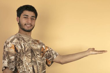 Genç adam bej renkli arka plan üzerinde elini tutar