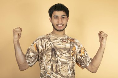 Genç adam bej arka planda yumruğunu kaldır.