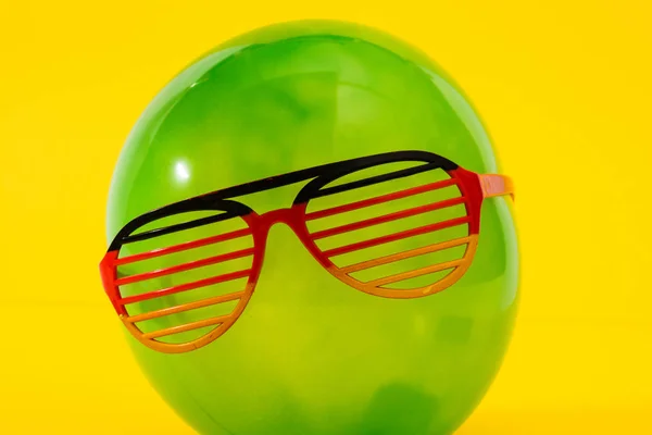 Zielony Balon Zabawy Okulary Żółtym Tle — Zdjęcie stockowe