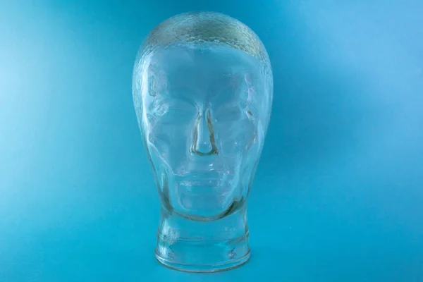 明るい青色の背景でヘッド形状のガラス — ストック写真