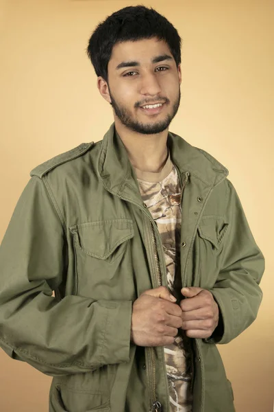 绿色军事夹克的年轻人在米色背景 — 图库照片