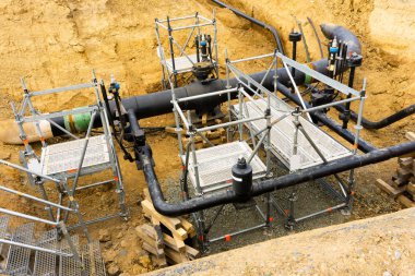 Görünürde hiçbir insan ile metalik iskele ve derin çukur içinde merdiven arasında siyah boru çalışan