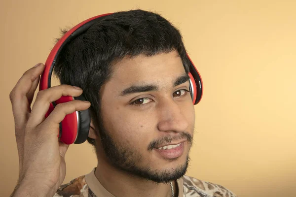 Junger Mann Mit Kopfhörer Hört Musik Auf Beigem Hintergrund — Stockfoto