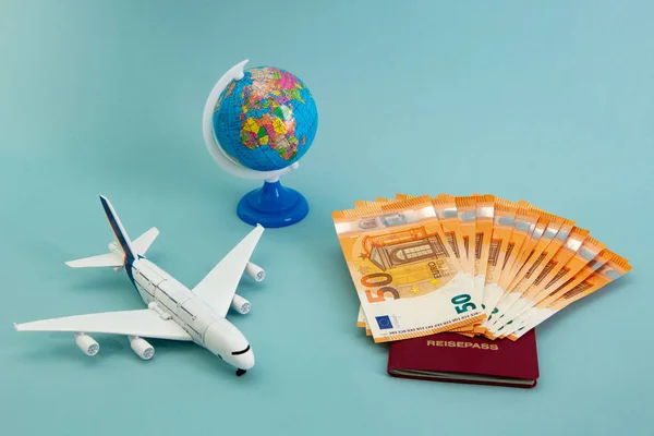 Summer Vacation Concept with toy boat, plane, globe and fifty Euro Banknotes on blue background