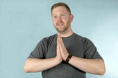 El ele tutusun tarafına, stüdyo arka planı arıyorum dua ile genç adam portresi yarım vücut.