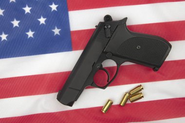 Arka planda Amerikan bayrağı üzerinde mühimmat bulunan tabanca.
