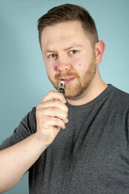 Buharlaştırıcıyı elinde tutarken elektronik sigara içen genç bir adam.