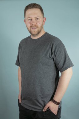 Gri tişört ikindilerde frontal stüdyo portre yakından cebinde el ile kameraya bakarak gündelik genç adam sakallı