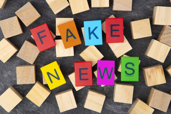 Concept: Fake News with colorful Toy Letters and wooden cubes on dark background