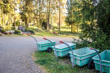Mezarlıkta arka arkaya plastik konteynırlı tekerlekli tramvaylar.