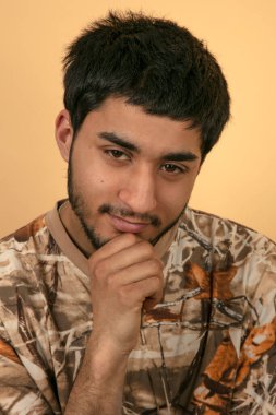 Bej arka planda eli çenesinde arkadaş canlısı genç bir adam.