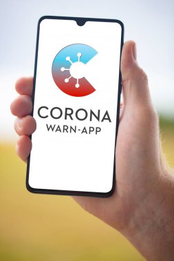 WETZLAR; GERMANY 2020-08-26, CORONA APP Resmi Alman Corona Uyarı Uygulaması cep telefonuyla bulanık arkaplanda tutuluyor