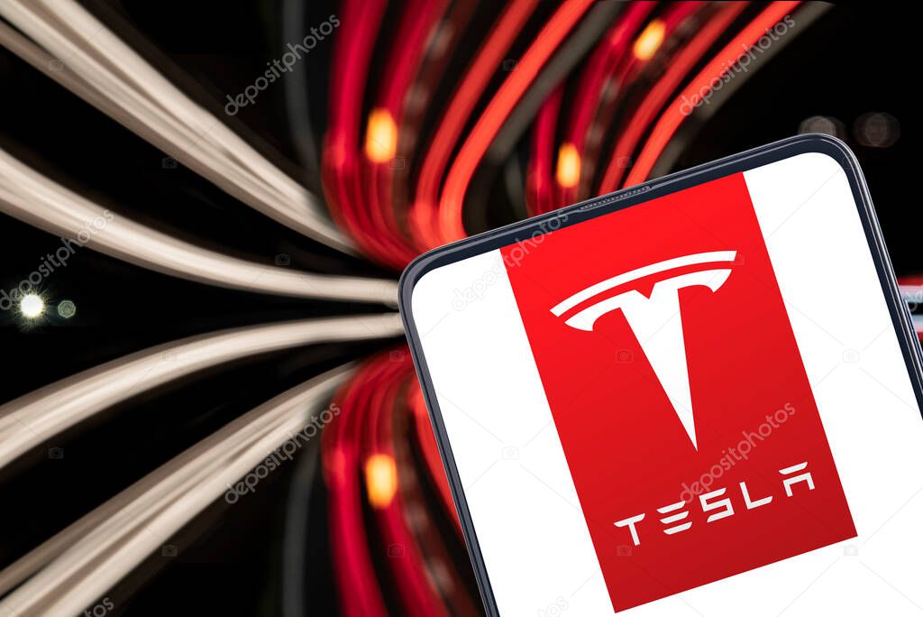 GERMANY - WETZLAR, 2019-10-14 TESLA LOGO on a smartphone with dynamic background in red and briht lines