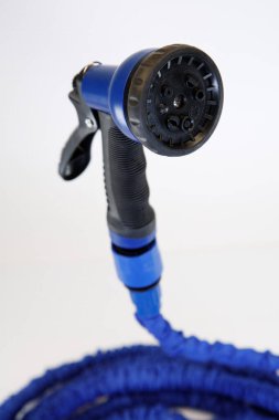 Mavi bahçe hortumunun çok fonksiyonlu sprey hortumu beyaz arka planda izole edilmiş, sulanmaya hazır.
