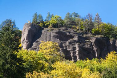 Sonbaharda granit bir tepenin üzerindeki ağaçlar mavi gökyüzüyle