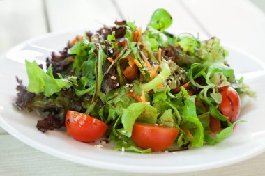 Taze sebze salatası, beyaz tabakta roka ve seçici odaklı.
