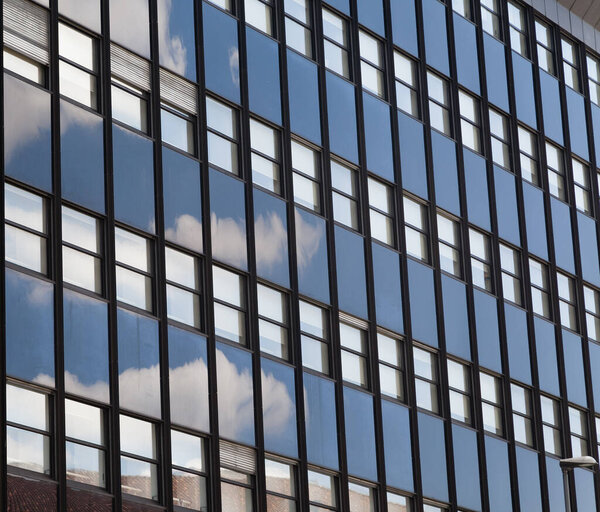 Rows of office building windows in frames with cloud reflection
