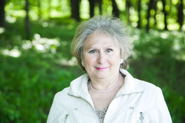 Ormanda gülümseyen yaşlı kadın portresi. 