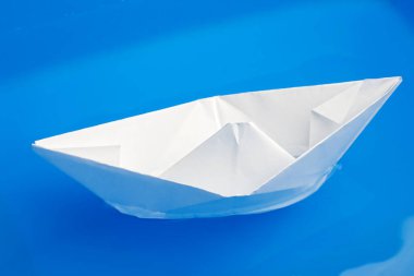 Seçici odaklı mavi su üzerine katlanmış kağıt geminin yakın plan görüntüsü 