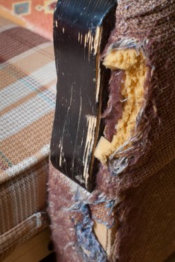 Seçici odaklı bir evcil hayvan tarafından kanepenin yırtılmış ve çizilmiş köşesi.