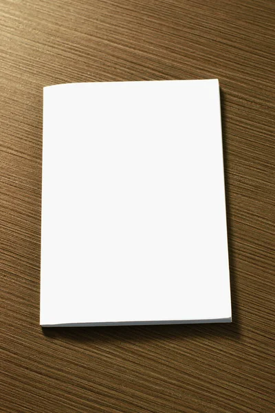 Vertical shot of blank notebook cover on wooden table with selective focus