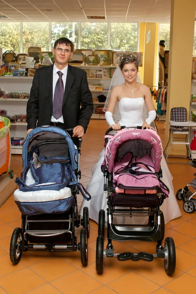 笑顔カップルの新婚夫婦とともに空の赤ちゃん馬車店で — ストック写真
