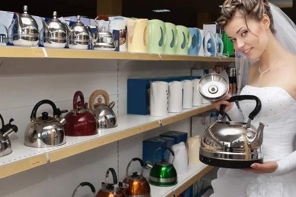 Smiling bride choosing tea pot in household appliances store