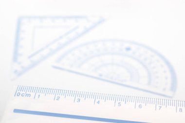 Arka planda bulanık açılı açıölçer ve üçgen ile mavi ölçüm cetvelinin yakınlaştırılması