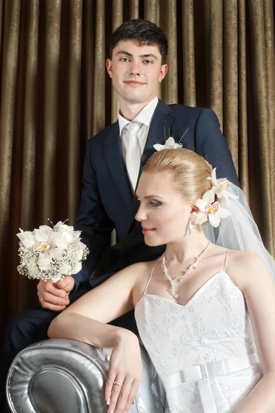 Bruid Met Bloem Haar Bruidegom Zit Achter Tegen Bruin Gordijn — Stockfoto