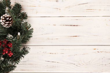 Noel çelenk koniler ve beyaz ahşap zemin üzerinde kırmızı meyveler