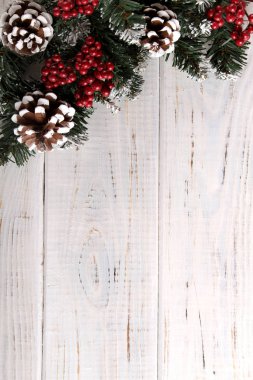 Çam dalları, koni ve beyaz ahşap zemin üzerinde kırmızı meyveler. Noel ve yeni yıl için arka plan