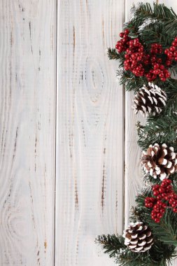 Çam dalları, koni ve beyaz ahşap zemin üzerinde kırmızı meyveler. Noel ve yeni yıl için arka plan