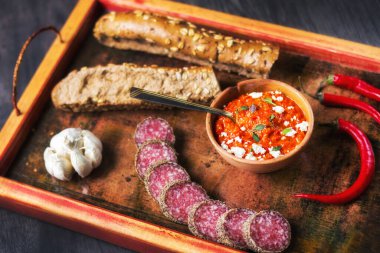 Basit Balkan yiyecekleri ile Rustik ahşap tepsi - ayvar yayılımı, ekmek, et, sarımsak ve kırmızı biber (seçici odak)