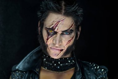 Profesyonel makyaj kurt adam Wolverine izleri ve turuncu göz ile.