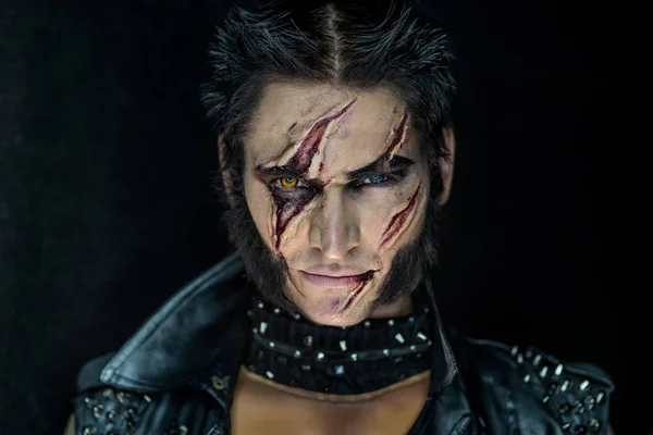 Professional make-up werewolf Wolverine with scars and orange eye.