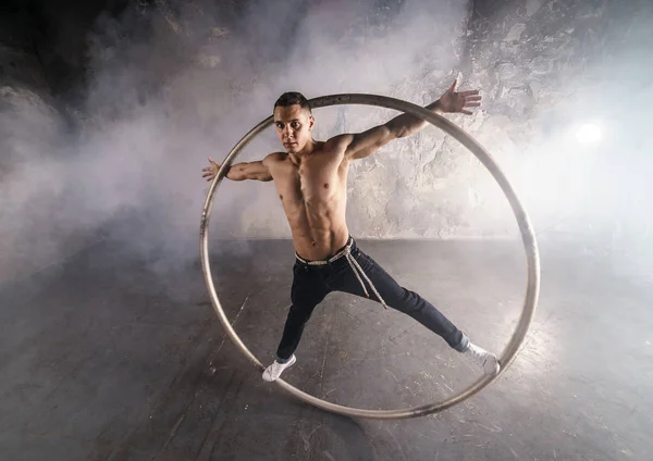 Strong circus performer spinning in the cyr wheel