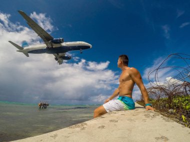 Kaslı adam sahilde deniz Karayip Denizi üzerinde uçan uçak iniş izliyor. Montego Bay. Jamaika