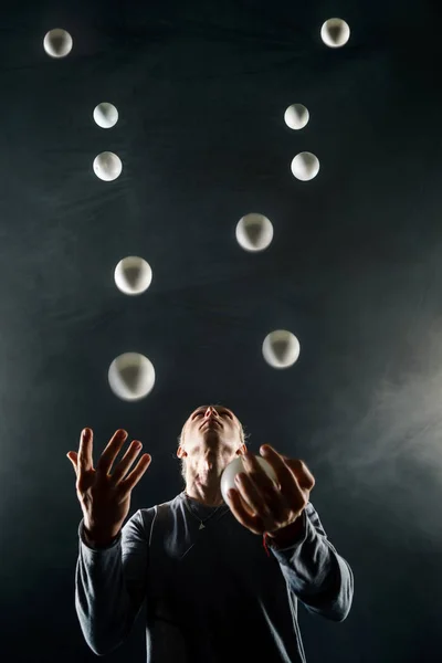 Siyah arka plan üzerine beyaz topları ile sarışın hokkabazlık yapmak