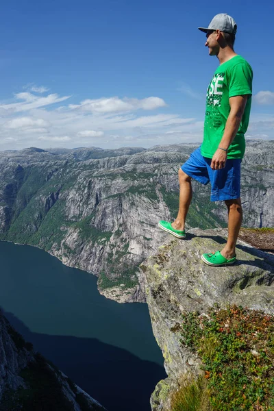 Молодий мандрівник людини, стоячи на краю скелі і, дивлячись на горах. Сонячний зимовий день в Норвегії — стокове фото
