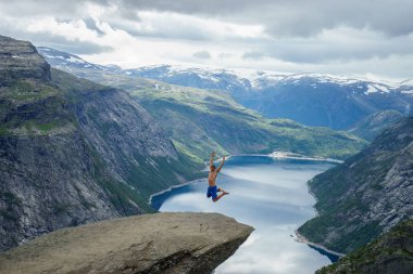 Genç adam atlamak kenarında Trolltunga. Norveç