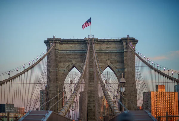 Vista de perto de uma das torres estruturas da ponte de Brooklyn, voando as estrelas e listras no topo — Fotografia de Stock