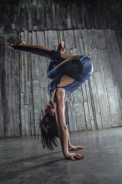 Genç kadın Acrobat ayakta yandan fotoğraf Studio gri arka plan üzerinde. Esnek kadın sirk jimnastik, jimnastik amut.