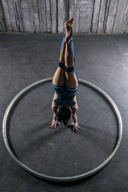 Genç kadın acrobat yandan büyük metal çember içinde ayakta. Jimnastik amut.